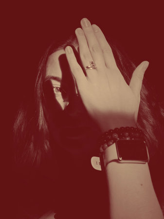Noir vintage shot in red, where a woman hides her face with the shadow of her palm