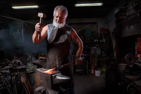Blacksmith with brush handles the molten metalの写真素材