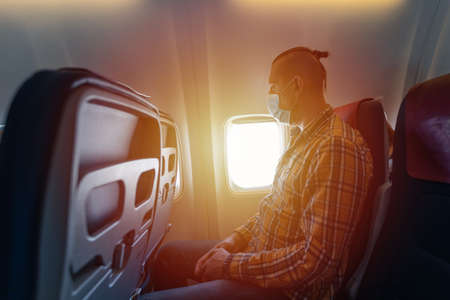 Man in medical mask inside airplane during flight.の写真素材
