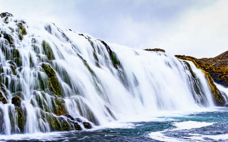 long exposure shot of a very broad waterfall over a rock formation, Iceland
