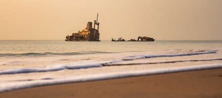Beach Sunset with abandoned shipwreck hazy sky little surfの写真素材