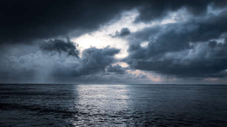 Dramatic sky with hugh clouds reflecting on ocean water surface