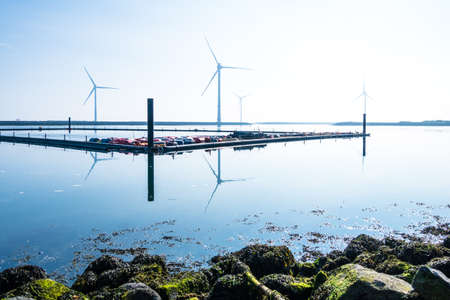 lookout from rocky coastline to small marina off the coast with wind turbines in the backgroundの写真素材