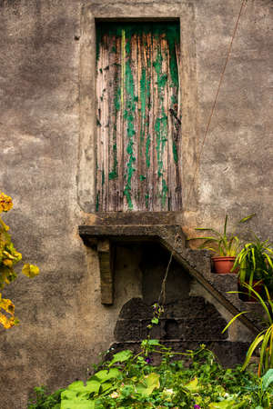 Old vegetable garden with weathered green wooden door in a brown stone wall on Madeira, Portugalの写真素材
