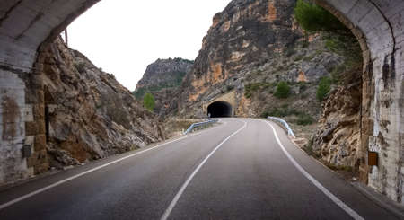 Driver point of view of winding country road through road tunnel in the mountainsの写真素材