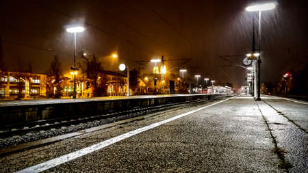 Freising, Germany - November 26, 2018: Rain falling on a railway station track at nightの写真素材