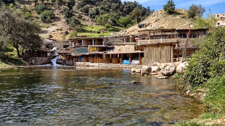 african village on the shore of a beautiful mountain lake in bright sunlight, Atlas mountains, Moroccoの写真素材