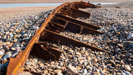 close-up of rusty ship wreck on stone beach almost fully covered by pebblesの写真素材