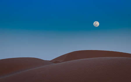 full moon over sand dunes in sahara desertの写真素材
