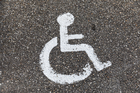 close-up of a wheelchair symbol as handicapped parking only sign on tarmac road from above
