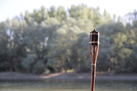 Bamboo torch with blurred trees in the backgroundの写真素材