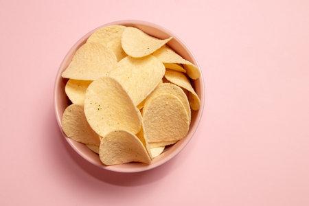 Potato chips in a bowl on pink background. Top view.の写真素材