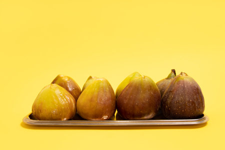 Fresh figs on a metal plate over yellow backgroundの写真素材