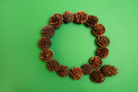 Christmas pine cones wreath on a green background. Flat lay circle frame.の写真素材