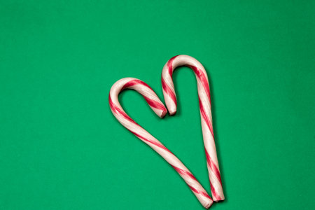 Heart made with candy canes on green backgroundの写真素材