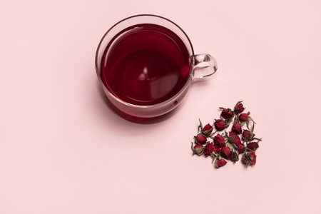 Red tea in a glass cup and rosebuds on a pink backgroundの写真素材