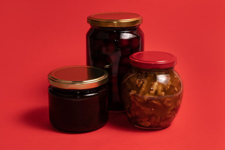 Jars of honey and jams on red backgroundの写真素材