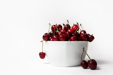 Fresh ripe cherries in a white bowl on white backgroundの写真素材