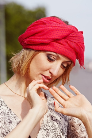 Beautiful girl with a red scarf on a stone embankment.の写真素材