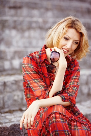 Beautiful girl in a red dress on the granite steps of theの写真素材