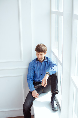 Near windows man in shirt poses for photographの写真素材