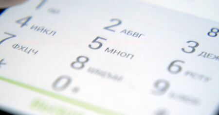 young handsome man sitting on a bench looking at his smartphone screen. The guy reads the message on the phone. Correspondence on the smartphone outdoor.の写真素材