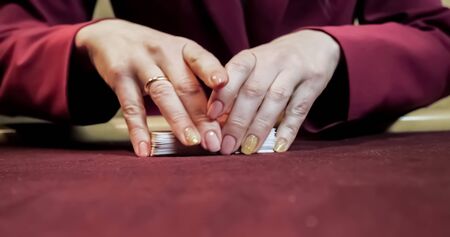 Dealer sitting in a casino at table while holding and distributing cardsの写真素材