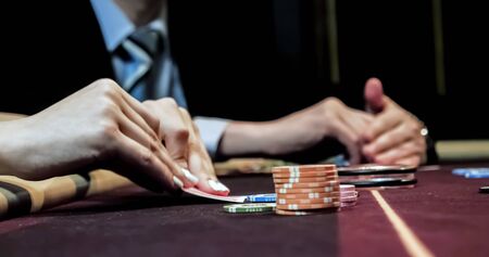 Dealer sitting in a casino at table while holding and distributing cardsの写真素材