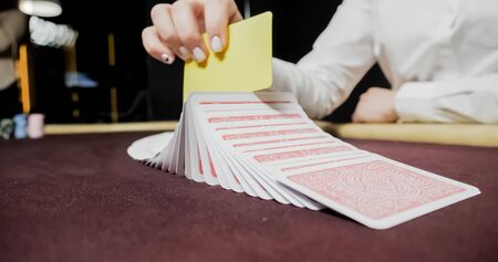 Dealer sitting in a casino at table while holding and distributing cardsの写真素材