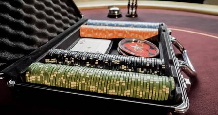 stacks of colorful poker chips and cards in case on red cloth in casino gambling chance