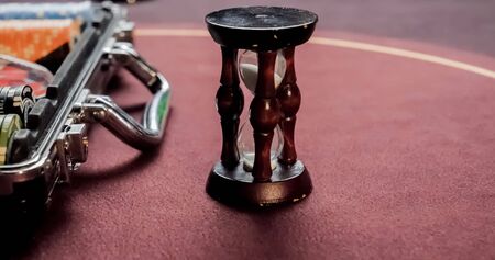 Burgundy casino table. Hourglass and poker chips on a red background
