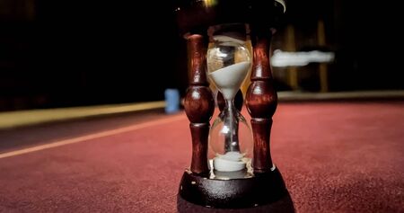 Burgundy casino table. Hourglass and poker chips on a red background