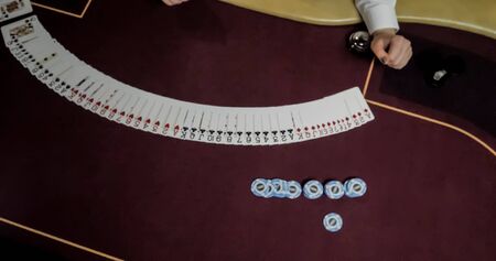 Dealer sitting in a casino at table while holding and distributing cards