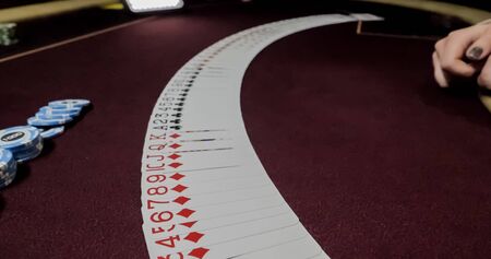 Dealer sitting in a casino at table while holding and distributing cards