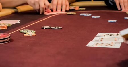 Dealer sitting in a casino at table while holding and distributing cardsの写真素材