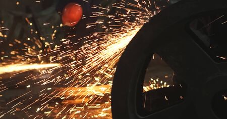 Working in a mask and headphones cleans joints angle grinder on metal parts blanks
