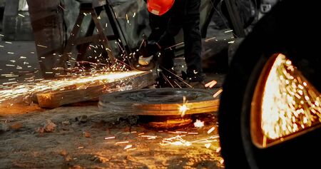Working in a mask and headphones cleans joints angle grinder on metal parts blanks