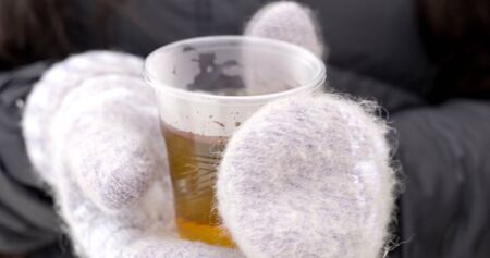 Hot drink in plastic cup in hands on bright background. Ecology conceptの写真素材