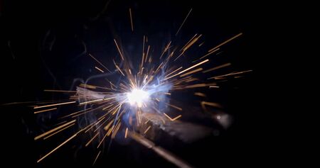 welder working with electrode at semi-automatic arc welding in manufacture production plant....
