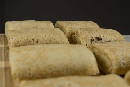 Cold pancakes with stuffing, on wooden blackboard. On a dark background