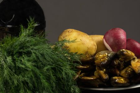 Young potatoes and smoked fish, young onions and dill on the board, a bottle of dark beerの写真素材