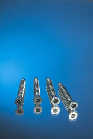 Countersunk wood screws on a blue background. mirror reflection