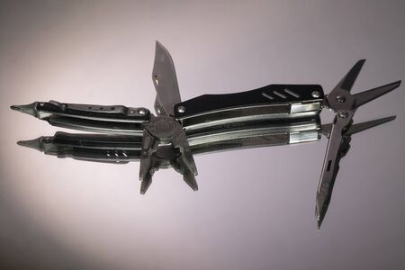 grey swiss knife isolated on white background. mirror reflection