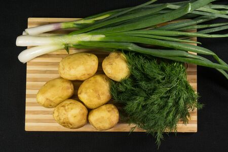 Raw fresh organic potatoes on black wooden table against dark background. Space for textの写真素材
