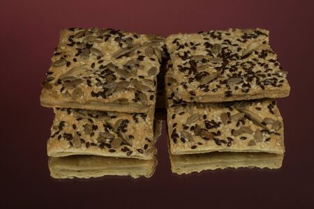 Puff pastry sticks with sesame and poppy seeds isolated on red mirror background