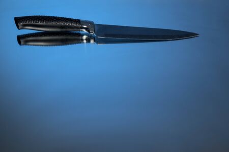 A large knife sits on a mirror backgroundの写真素材