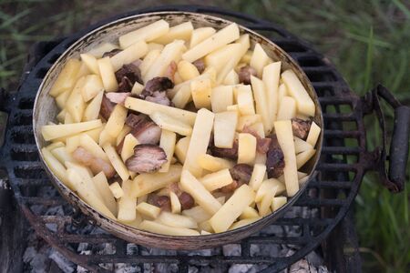 jacket potatoes, squash and sausages are cooked in a large frying pan on an open fire. Barbecue on the natureの写真素材