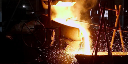 Metal smelting in a metallurgical plant. Sparks fly out of the furnace.