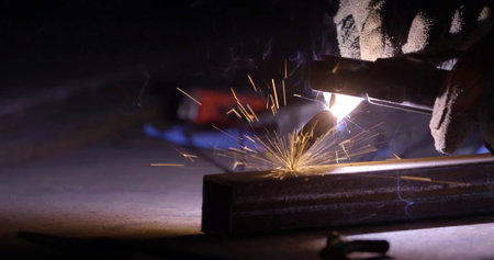Sparks while welder uses electric arc welding machine to weld steel.