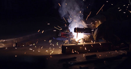 Welder at work in a car factory. Sparks while welder working